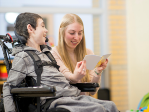 A woman helping a disabled child with reading.